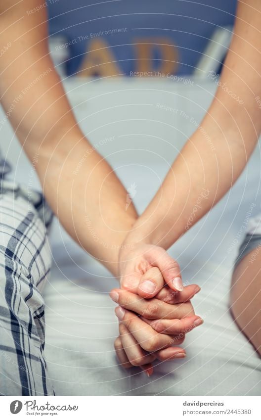 Junges Paar, das Händchen hält und über einem Bett sitzt. Lifestyle Glück schön Erholung Schlafzimmer Frau Erwachsene Mann Familie & Verwandtschaft Hand Liebe