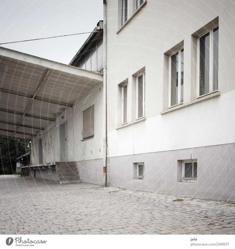 lieferzone Himmel Haus Industrieanlage Platz Bauwerk Gebäude Architektur Mauer Wand Fenster Tür Dach trist grau weiß Farbfoto Gedeckte Farben Außenaufnahme