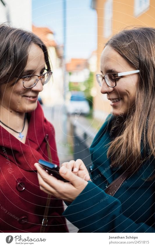 Zwillingsschwestern schauen gemeinsam auf ein Smartphone Lifestyle Stil Freude Glück Mensch feminin Junge Frau Jugendliche Geschwister Schwester Leben 2