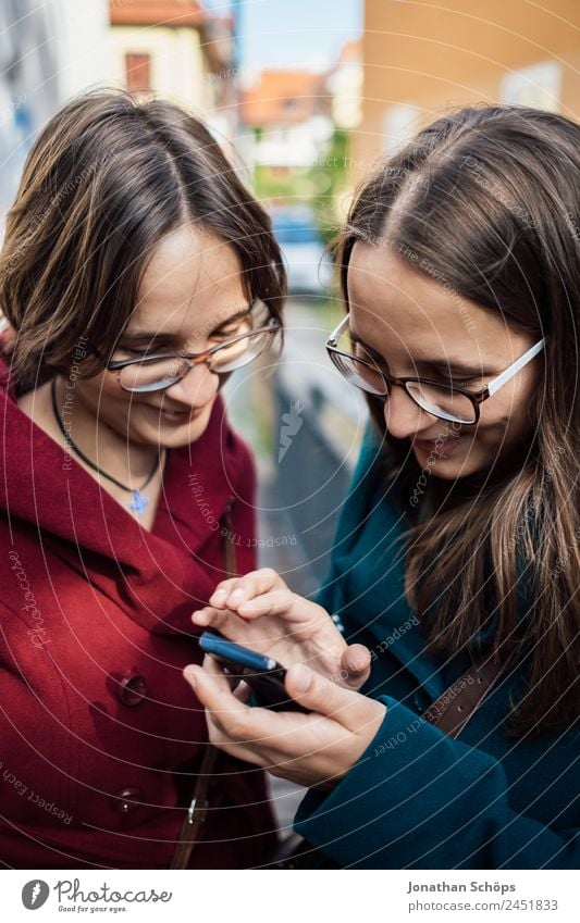 Zwillingsschwestern schauen gemeinsam auf ein Smartphone Lifestyle Stil Freude Glück Mensch feminin Junge Frau Jugendliche Geschwister Schwester 2 Fröhlichkeit