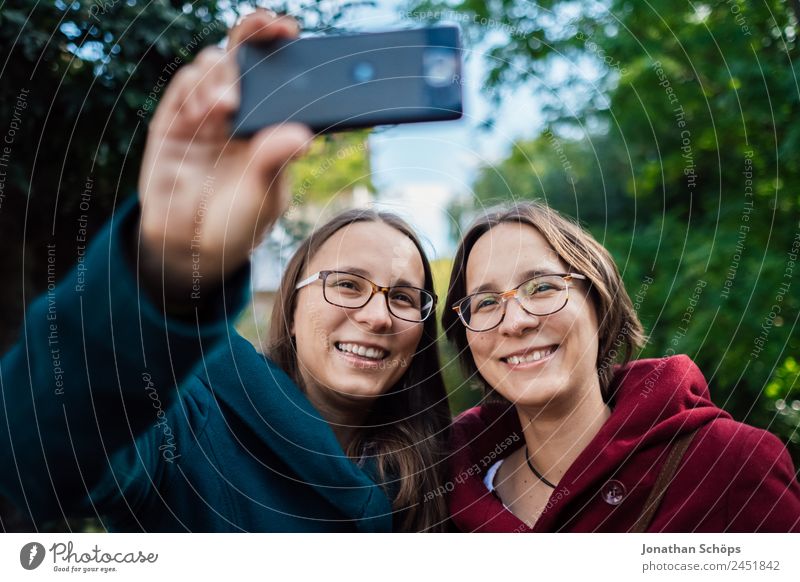 fröhliche Zwillingsschwestern machen ein Selfie mit dem Smartphone Lifestyle Stil Freude Glück Mensch feminin Junge Frau Jugendliche Geschwister Schwester Leben