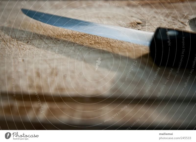 Messer liegt auf Holzbrett Schneidebrett Manuelles Küchengerät scharf braun schwarz silber Klinge matt schneiden Furche Spitze Metall gefährlich Risiko Farbfoto