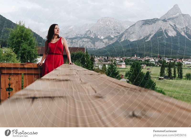 Young woman enjoying the view of the alps from a balcony feminin Junge Frau Jugendliche Erwachsene 1 Mensch 18-30 Jahre 30-45 Jahre Erholung Kleid rot Balkon