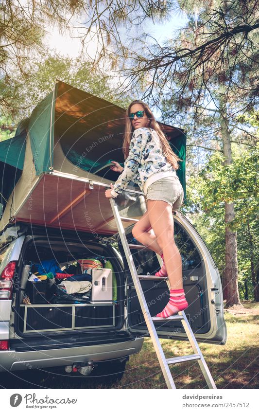 Frau steht in einer Leiter und öffnet das Zelt über dem Auto. Lifestyle Freude Glück Erholung Freizeit & Hobby Ferien & Urlaub & Reisen Ausflug Abenteuer