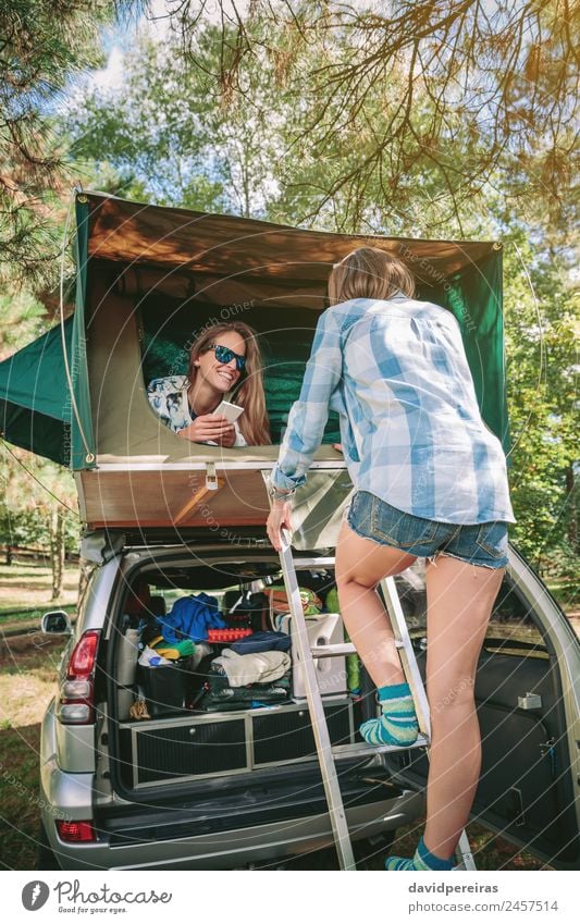 Frau geht die Leiter hinauf, um über dem Auto zu zelten. Lifestyle Freude Glück Erholung Freizeit & Hobby Ferien & Urlaub & Reisen Ausflug Abenteuer Camping