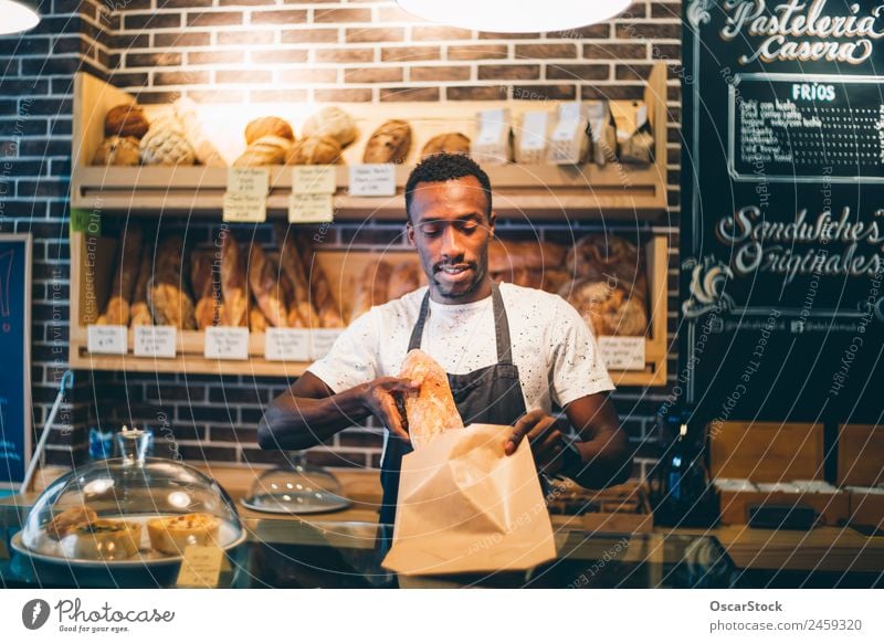 Der Afrikaner arbeitet in der Konditorei. Brot Tafel Arbeit & Erwerbstätigkeit Beruf Business Mensch Mann Erwachsene Lächeln stehen verkaufen Fröhlichkeit