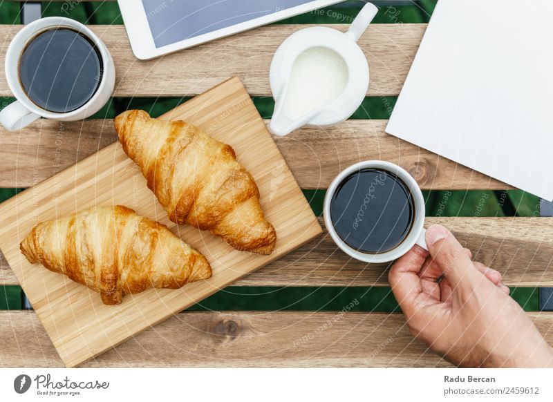 Frühstück am Morgen im Grünen Garten mit französischem Croissant, Kaffeetasse, Orangensaft, Tablette und Notizbuch auf Holztisch Tisch Hintergrundbild weiß