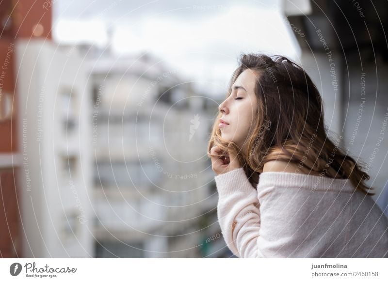 Frau schaut von ihrem Balkon auf die Stadt. Lifestyle schön Gesicht Wohnung Mensch Erwachsene Stadtzentrum Straße Pullover Denken authentisch natürlich Gefühle