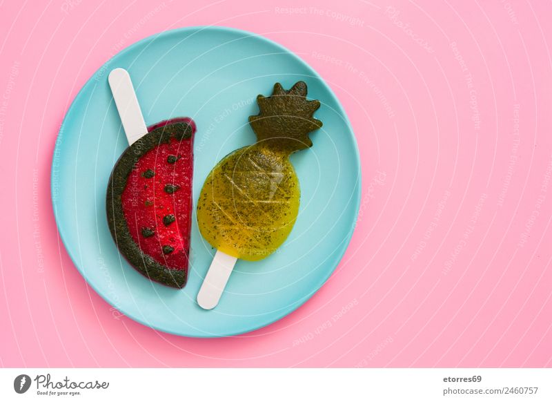 Ananas- und Wassermelonenstiele auf rosa Hintergrund. Lebensmittel Frucht Dessert Speiseeis Süßwaren Ernährung Sommer Sommerurlaub blau gelb grün rot Eis Snack