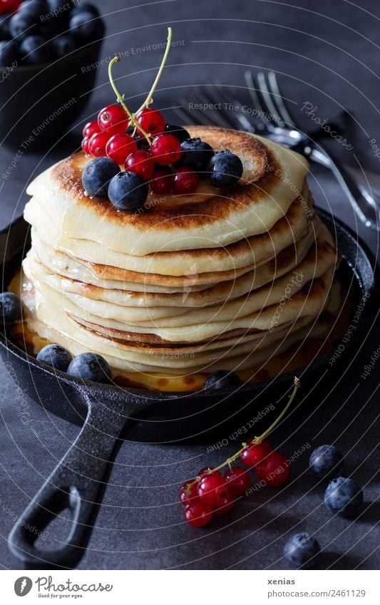 Pfannkuchen mit Johannisbeeren und Blaubeeren in gusseiserner Pfanne stehen auf dunklem Tisch Frucht Gußeisen Teigwaren Ernährung Frühstück Büffet Brunch