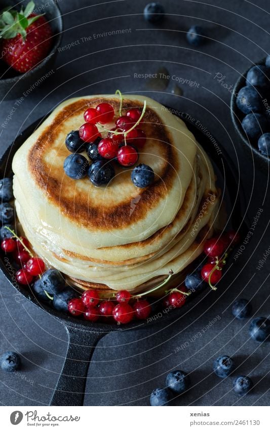 Kleine Pfannkuchen mit Blaubeeren und roten Johannisbeeren in gusseiserner Pfanne Frucht Teigwaren Backwaren Erdbeeren Zuckersirup Frühstück Büffet Brunch