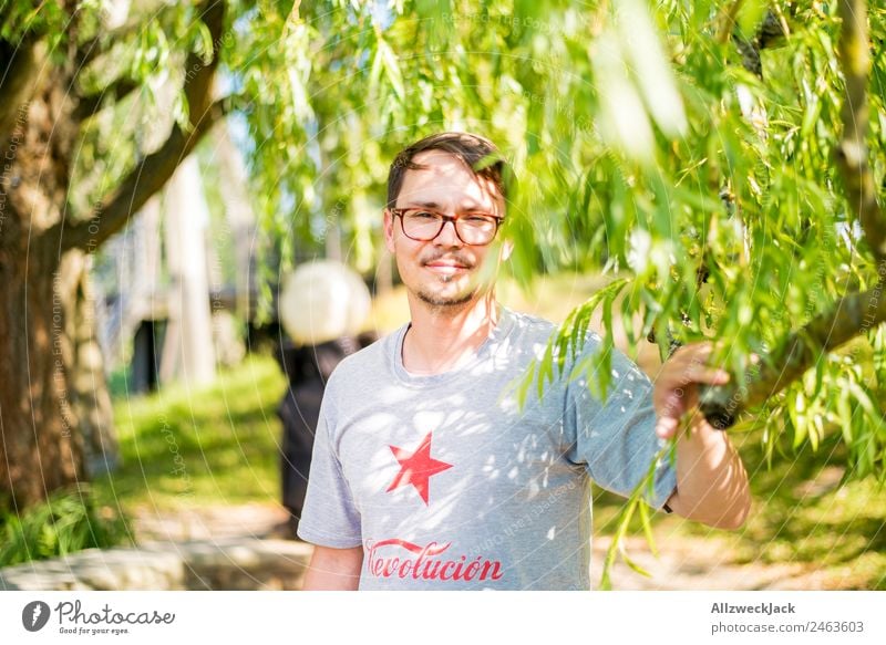 Portrait von einem jungen Mann in der Natur Porträt Junger Mann 1 Mensch Brille grün Tag sitzen Erholung Pause ausruhend genießen Park Ferien & Urlaub & Reisen