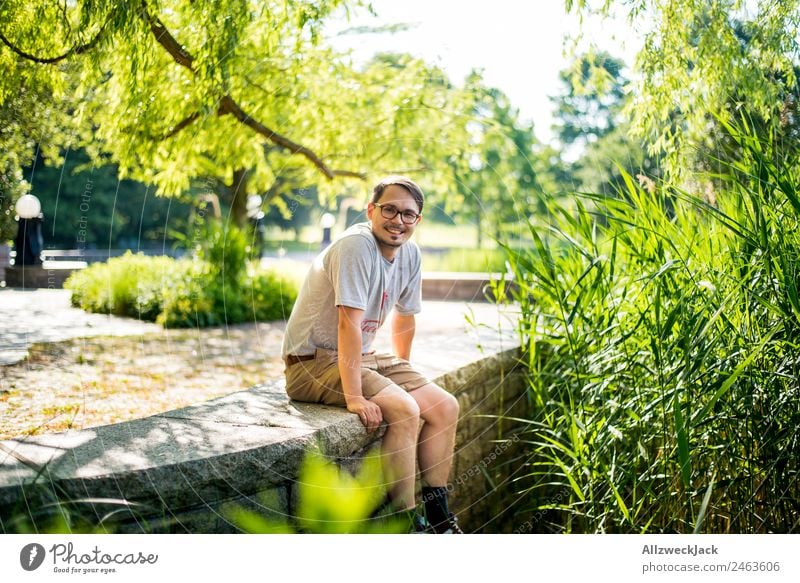 Portrait von einem jungen Mann in der Natur Porträt Junger Mann 1 Mensch Brille grün Tag sitzen Erholung Pause ausruhend genießen Park Ferien & Urlaub & Reisen