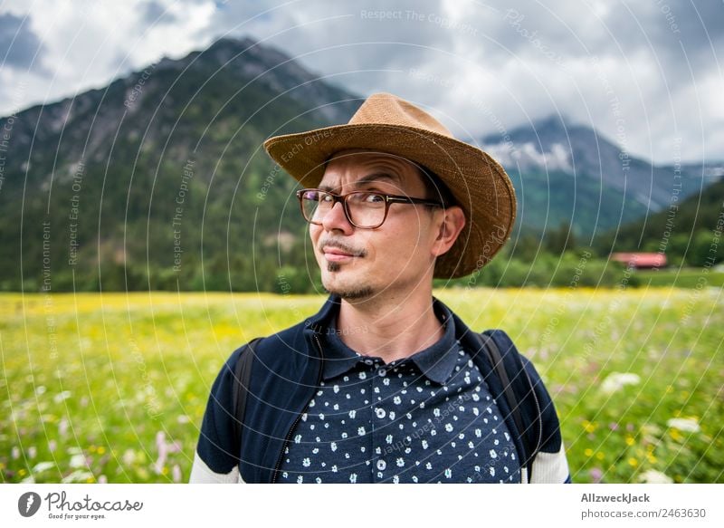 junger Mann mit Hut vor Bergpanorama Tag Schönes Wetter Wolken Natur grün Baum Wald Berge u. Gebirge Idylle Ferien & Urlaub & Reisen Reisefotografie wandern