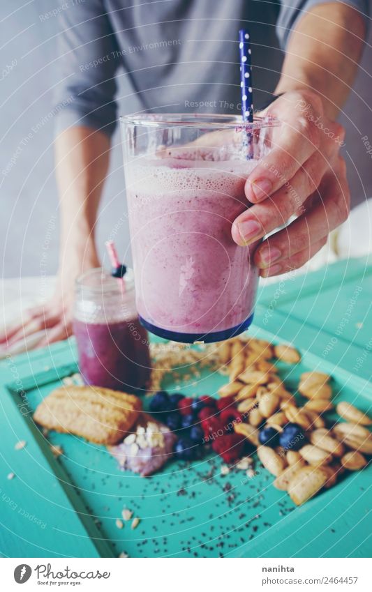 Mann hält einen Milchshake aus Beeren und Haferflocken. Frucht Dessert Mandel Plätzchen Frühstück Bioprodukte Vegetarische Ernährung Getränk trinken