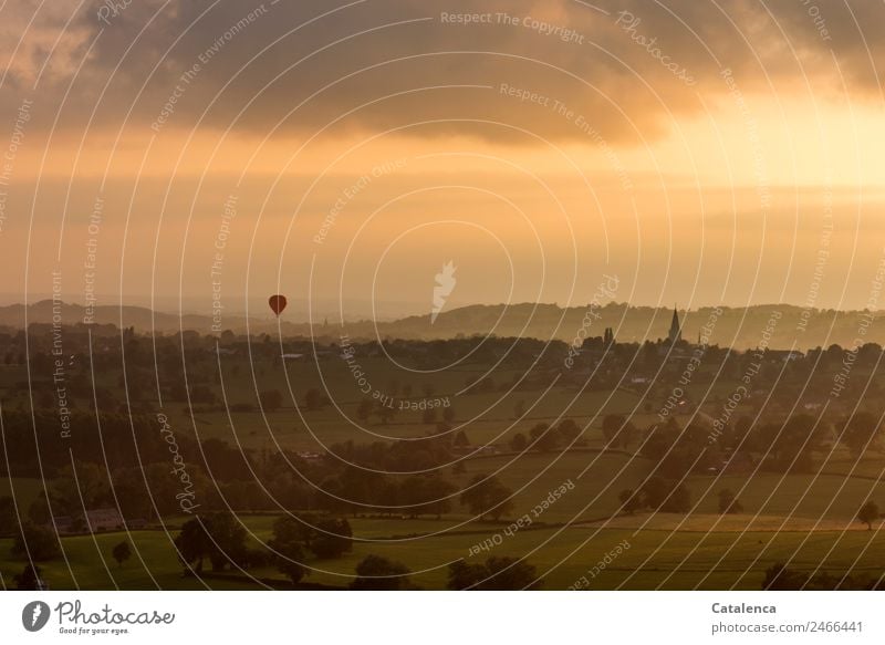 Heißluftballon am Horizont, die Sonne geht unter Ballonfahrt Landschaft Himmel Wolken Sommer Baum Sträucher Hecke Wiese Feld Hügel Dorf bevölkert Haus Turm