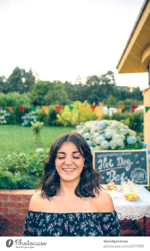 Junge Frau mit geschlossenen Augen, die über den Naturhintergrund lacht. Mittagessen Limonade Lifestyle Freude Glück Freizeit & Hobby Sommer Garten Tisch Tafel