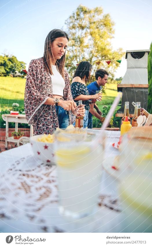 Frau öffnet Bierflasche am Sommergrill Essen Mittagessen Getränk Limonade Alkohol Flasche Trinkhalm Lifestyle Freude Glück Freizeit & Hobby Garten Tisch