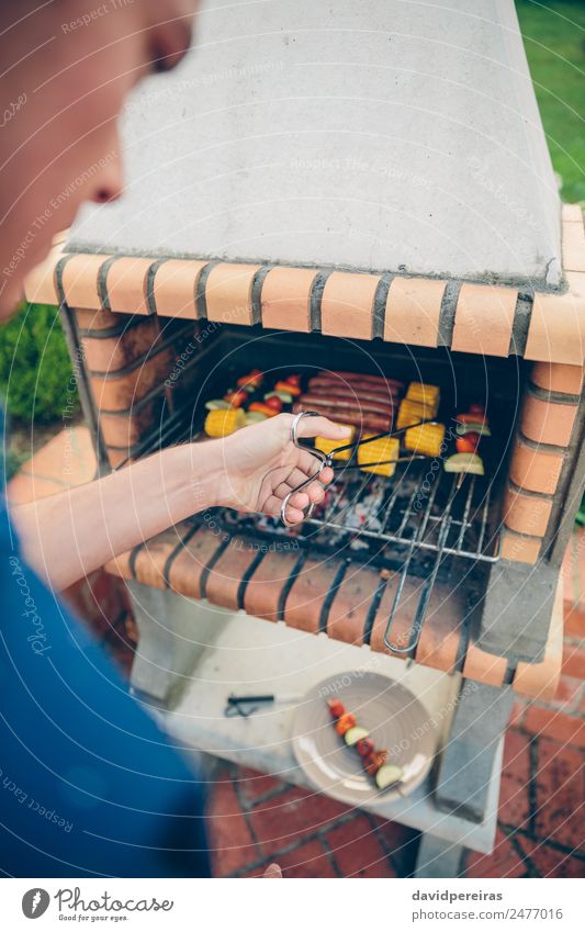 Nicht erkennbarer junger Mann beim Kochen von Mahlzeiten am Grill Wurstwaren Gemüse Lifestyle Freude Glück Erholung Sommer Garten Mensch Erwachsene Freundschaft