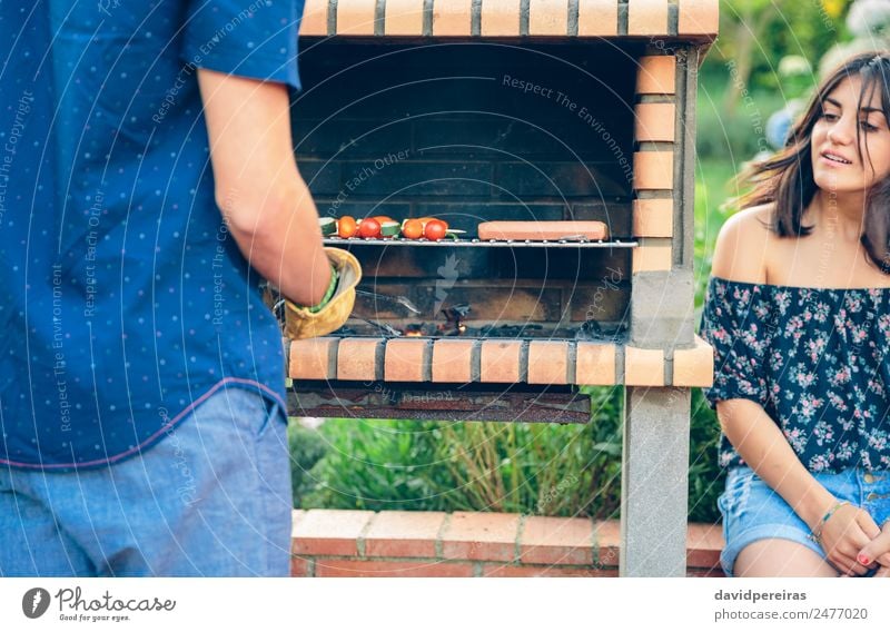 Mann kocht Würstchen und Gemüsespieße im Barbecue. Wurstwaren Lifestyle Freude Glück Erholung Sommer Garten sprechen Frau Erwachsene Freundschaft Hand Natur