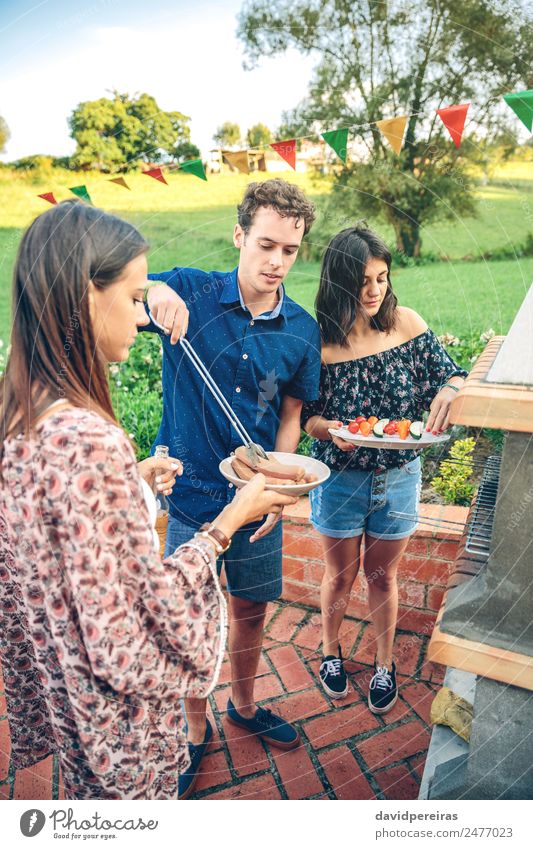 Gruppe von Freunden, die bei einem Sommergrill kochen. Gemüse Mittagessen Alkohol Bier Teller Flasche Lifestyle Freude Glück Freizeit & Hobby Garten sprechen