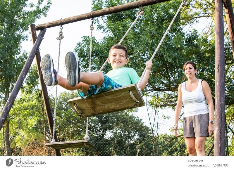 Mutter schwingt ihren Sohn auf einer Schaukel. Lifestyle Freude Glück schön Erholung Freizeit & Hobby Spielen Kind Mensch Junge Frau Erwachsene Mann Eltern