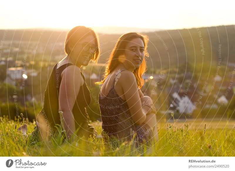 Zwei Frauen sitzen auf einer Wiese bei Abendlicht Lifestyle Mensch Junge Frau Jugendliche Erwachsene Geschwister Schwester Freundschaft 2 18-30 Jahre Umwelt