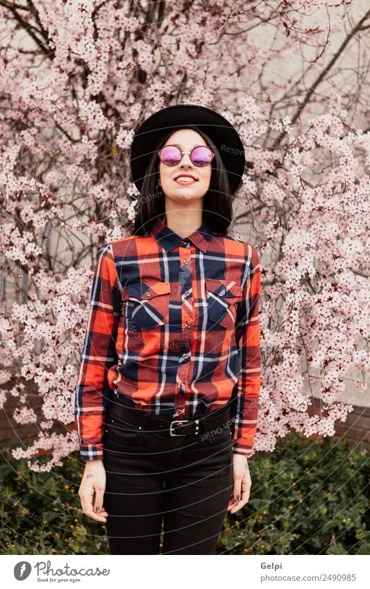 Brünettes Mädchen Stil Glück schön Gesicht Garten Mensch Frau Erwachsene Natur Baum Blume Blüte Park Mode Sonnenbrille Hut brünett Lächeln Fröhlichkeit frisch