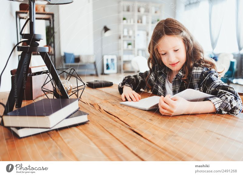 glückliches Schulmädchen, das Hausaufgaben macht. Kluges Kind, das hart arbeitet. Lifestyle lesen Tisch Erfolg Schule lernen Schulkind Kindheit Buch