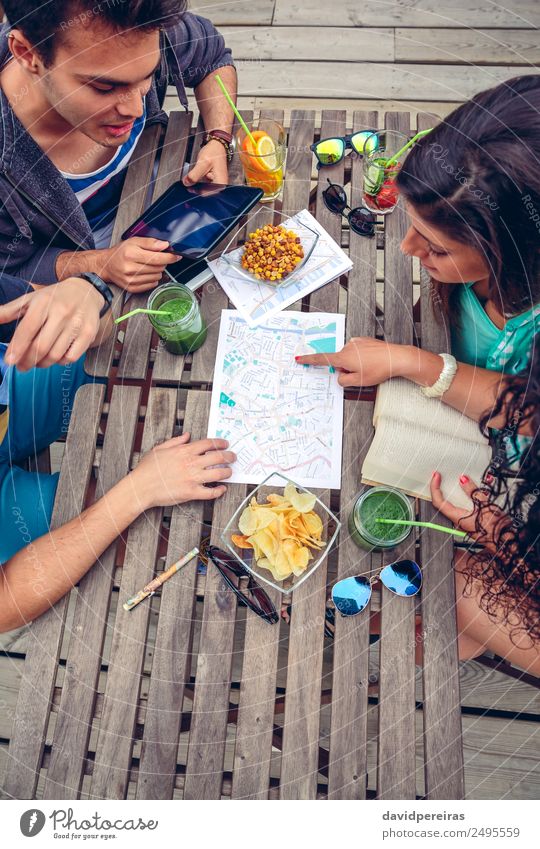 Junge Freunde, die die Karte über einem Tisch betrachten. Saft Lifestyle Ferien & Urlaub & Reisen Tourismus Ausflug Abenteuer Sommer Telefon