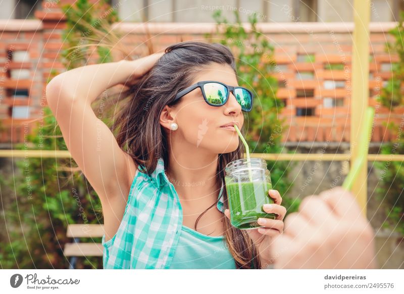 Frau mit Sonnenbrille, die im Freien grünen Gemüse-Smoothie trinkt. Frucht Ernährung Diät Getränk Saft Lifestyle Glück schön Sommer Garten Mensch Erwachsene