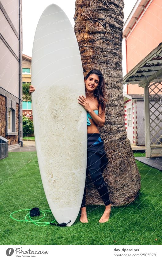 Surferin mit Bikini und Neoprenanzug mit Surfbrett. Lifestyle Freude Glück schön Ferien & Urlaub & Reisen Sommer Strand Garten Sport Mensch Frau Erwachsene Baum