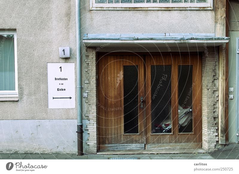 Der Briefkasten war böse Haus alt dreckig hässlich trist grau 1 Hausnummer Eingangstür Autofenster Fallrohr Vordach Dach Holz Glas Griff Backstein Glasbaustein