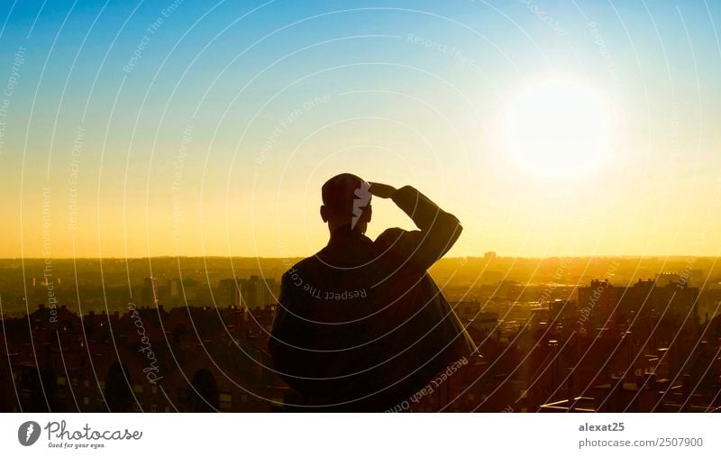 Ein Mann, der bei Sonnenaufgang die Stadt ansieht. Mensch Erwachsene Himmel Hochhaus Denken Blick stehen Einsamkeit Zukunft Rücken Hintergrund Großstadt