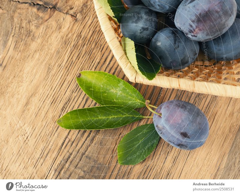 Frisch geerntete Bio Pflaumen in einem Korb auf Holztisch Lebensmittel Frucht Dessert Bioprodukte Vegetarische Ernährung Gesunde Ernährung Sommer Natur lecker