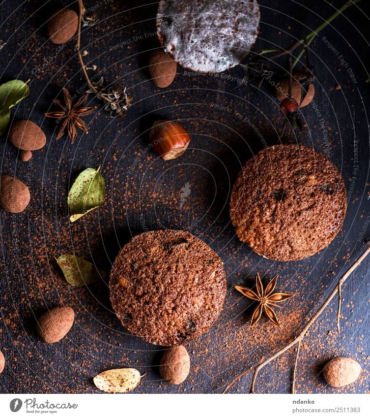 gebackene Muffins auf einem schwarzen Tisch Kuchen Dessert Süßwaren Frühstück Holz Essen frisch klein oben braun Pulver Hintergrund Bäckerei Schokolade