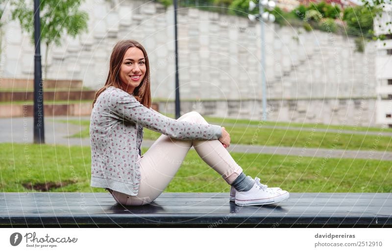 Schöne junge Frau auf der Parkbank sitzend Lifestyle Stil Glück schön Freizeit & Hobby Mensch Erwachsene Natur Herbst Gras Mode Bekleidung Jeanshose Jacke