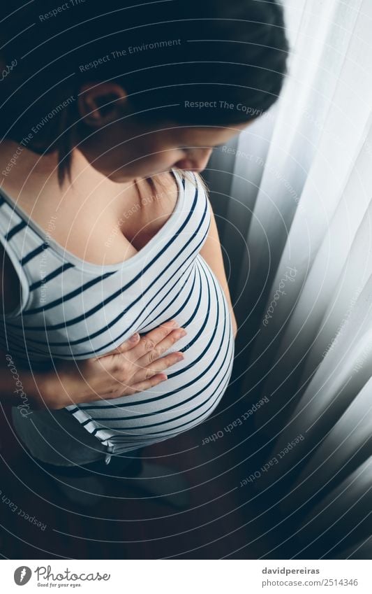 Schwangere Frau, die ihren Bauch ansieht. schön Leben Kindererziehung Mensch Baby Erwachsene Mutter Frauenbrust Hand Denken Liebe warten authentisch schwanger