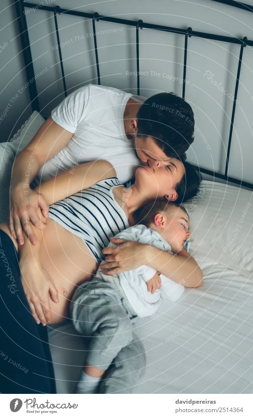 Schwanger, die ihre Partnerin mit ihrem Sohn küsst. Glück schön Leben Erholung Schlafzimmer Kind Mensch Baby Kleinkind Frau Erwachsene Mann Eltern Mutter Vater