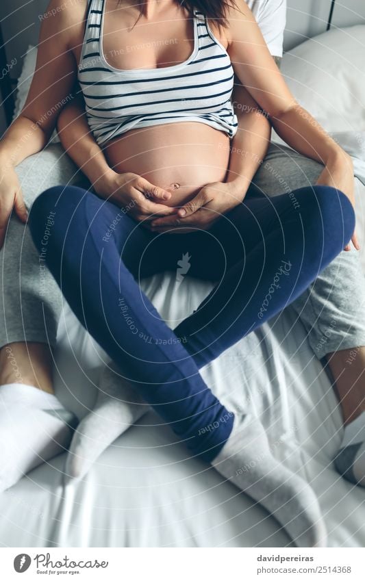 Schwangere Frau, die von ihrem Mann umarmt wird. Schlafzimmer Mensch Baby Erwachsene Eltern Mutter Vater Familie & Verwandtschaft Paar Partner Hand Liebe sitzen