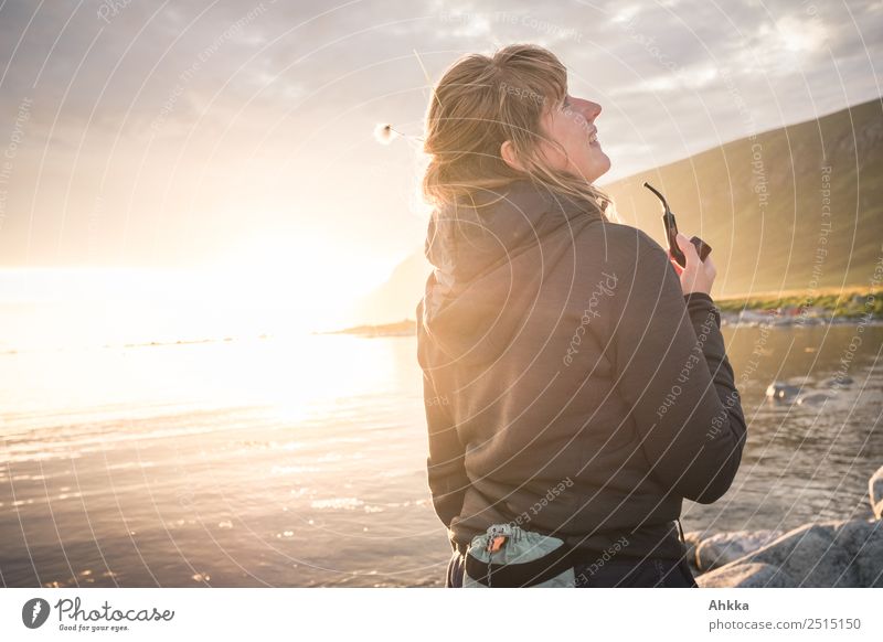 Junge Frau mit Pfeife im Gegenlicht am Meer in der Mitternachtssonne Freiheit Sonnenlicht Lebensfreude Zufriedenheit Lebensfreude & Lebensglü... Spaß haben