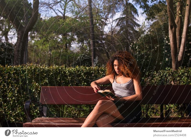 Afrofrau beim Lesen eines Buches auf einer Bank Lifestyle Glück schön Freizeit & Hobby lesen Sommer Schule lernen Mensch Frau Erwachsene Natur Baum Gras Park