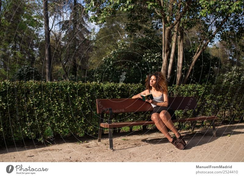 Afrofrau beim Lesen eines Buches auf einer Bank Lifestyle Glück schön Freizeit & Hobby lesen Sommer Schule lernen Mensch Frau Erwachsene Natur Baum Gras Park