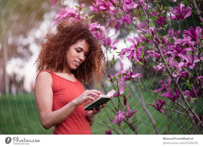 Afrofrau beim Lesen eines Buches im Freien Lifestyle Glück schön Freizeit & Hobby lesen Sommer Garten Schule lernen Mensch Frau Erwachsene Natur Baum Blume Gras