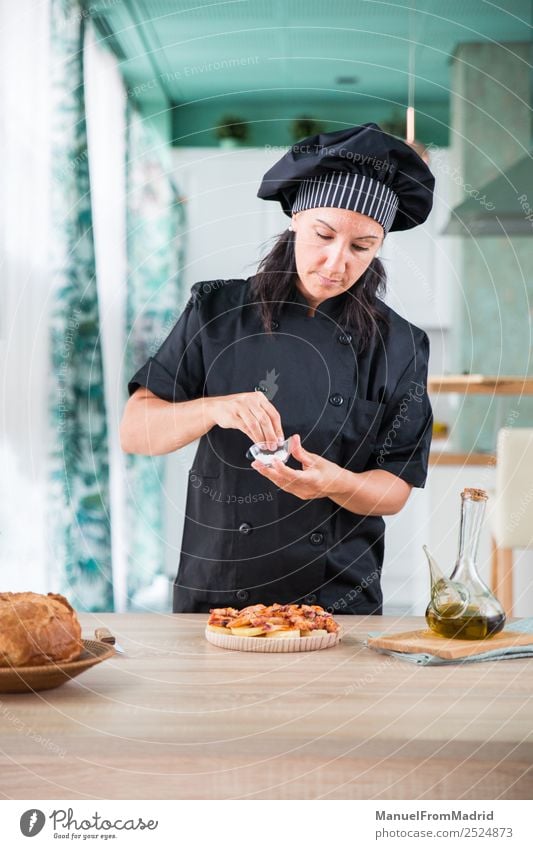 Köchin, die ein Gericht würzt. Kräuter & Gewürze Ernährung Teller Tisch Küche Mensch Frau Erwachsene Hand Hut Holz modern Küchenchef Koch Hinzufügen Salz