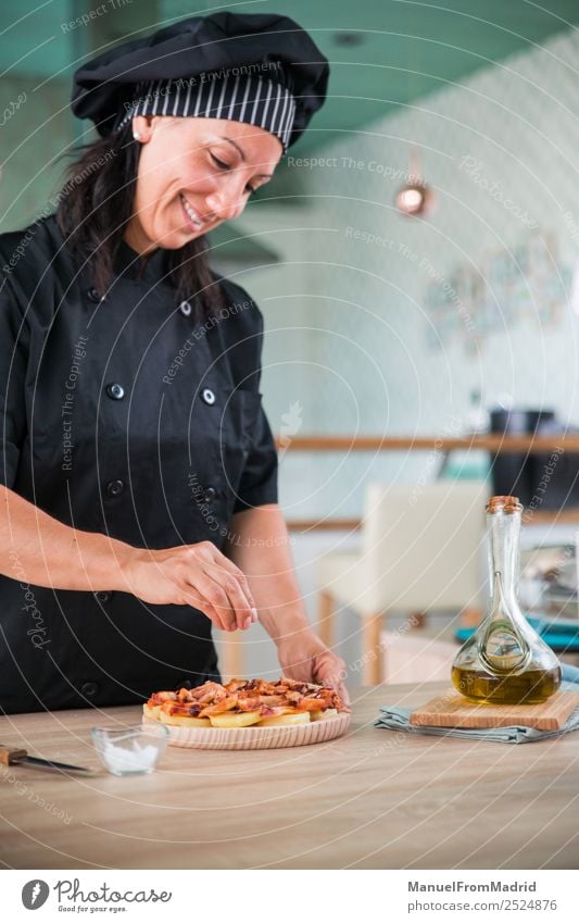 Köchin, die ein Gericht würzt. Kräuter & Gewürze Ernährung Teller Glück Tisch Küche Mensch Frau Erwachsene Hand Hut Holz Lächeln modern Küchenchef Koch