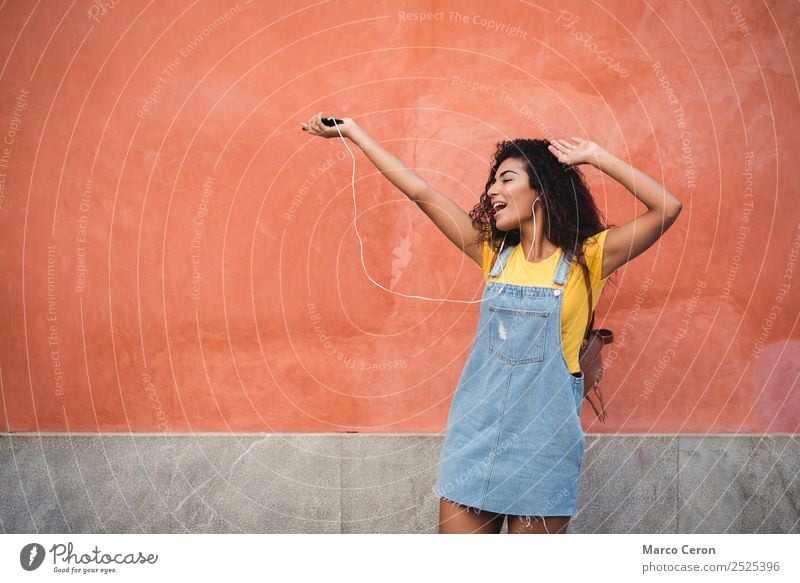 schönes gemischtes Mädchen, das auf der Straße fröhlich der Musik lauscht Afrikanisch schwarz blau braune Haare lässig celular krause Haare niedlich Tanzen Tag