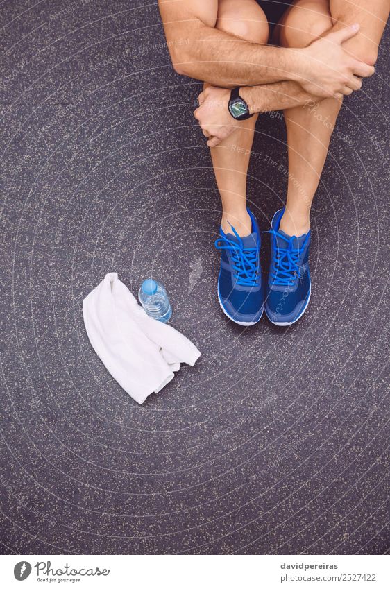 Sportlicher Mann sitzt mit Handtuch und Trinkflasche auf dem Boden des Fitnessstudios. Flasche Lifestyle Körper Freizeit & Hobby Mensch Erwachsene Arme