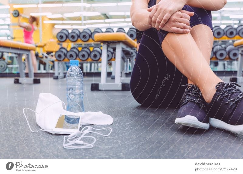 Sportliche Frau sitzt mit Hanteln, Wasser und Smartphone im Fitnessstudio. Flasche Lifestyle schön Körper Freizeit & Hobby Musik Telefon PDA Mensch Erwachsene