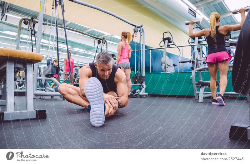 Männer, die sich dehnen und Frauen, die Kurzhantel-Übungen im Fitnessstudio machen. Lifestyle Glück schön Körper Freizeit & Hobby Club Disco Sport Mensch